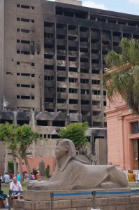 Old and new -- a sphinx in front of the Egyptian Museum against the burned out headquarters of Mubarak's political party.