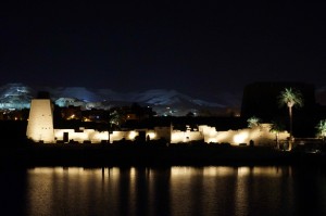 Karnak at night. The Valley of the Kings is lit up in the background.